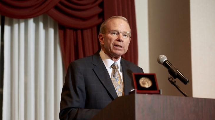 Business professor presents the Achievement in Business Award at a podium