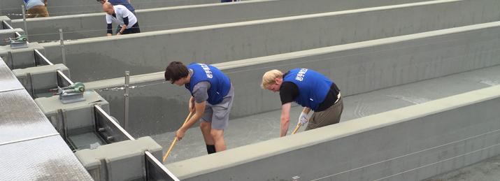 From left, in the foreground inside fish chute: OHIO Sophomore Nick Farris and Senior Ben Piper help to scrub clean the concrete fish-egg chutes at a local fish hatchery used to dispense fertilized salmon roe into a nearby river as part of the OHIO-IPU Tsunami Volunteer Project year six.