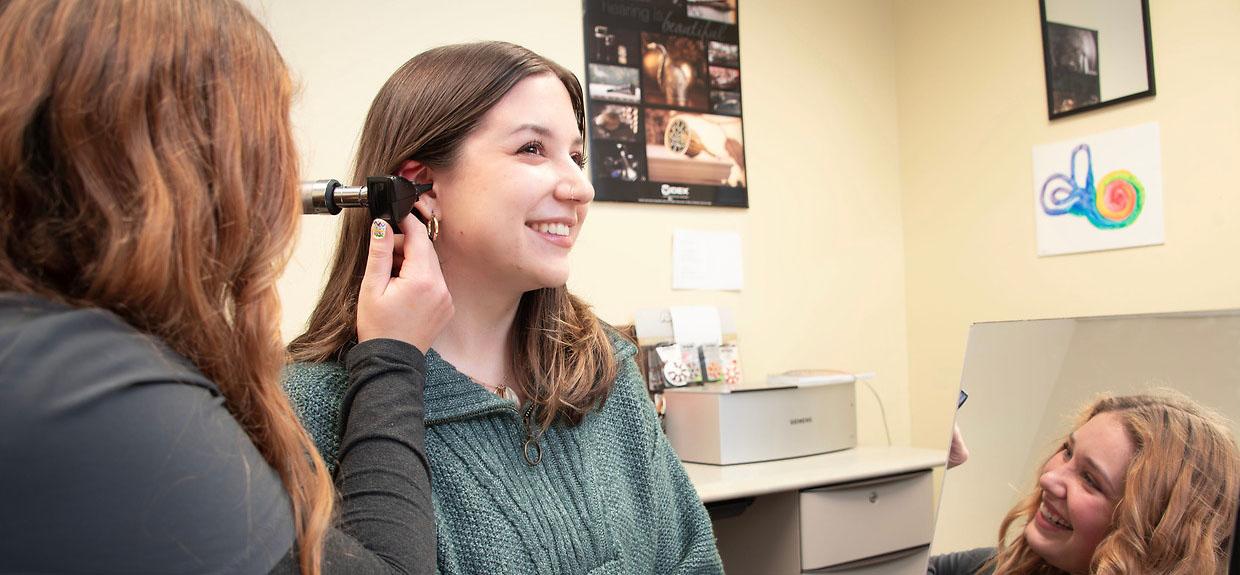 Audiologist looking in a patient's ear using tools