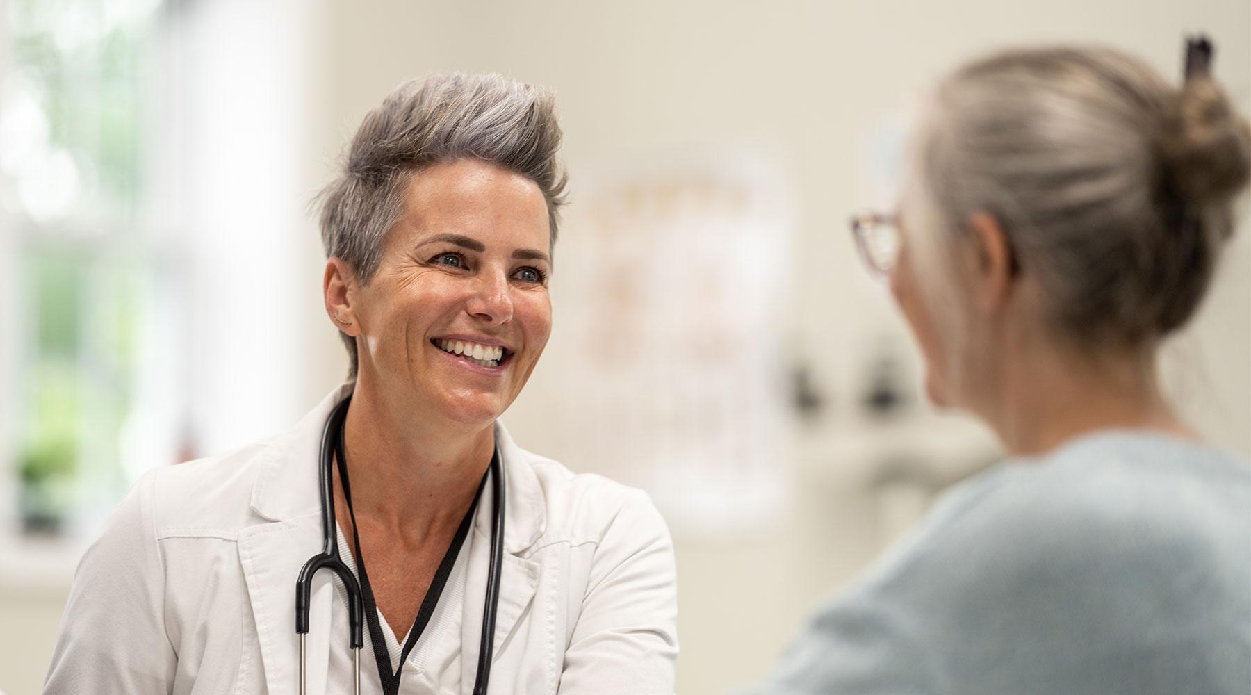 Smiling doctor in white jacket in front of patient
