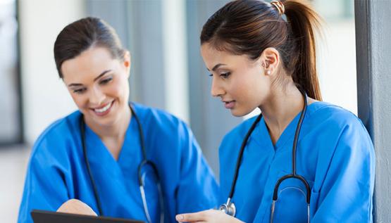 Two DNP students in scrubs reviewing chart on tablet