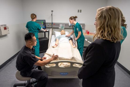Health studies students work on a mannequin simulation in a lab