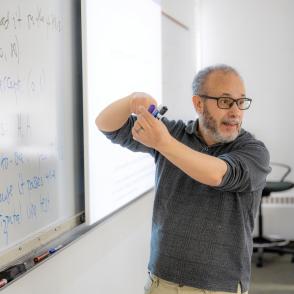 Teacher in a classroom presenting on a dry-erase board