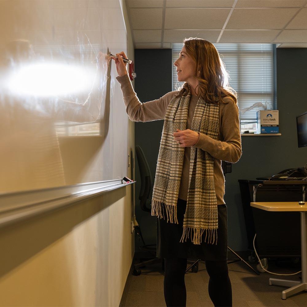 Teacher writing on a white board.