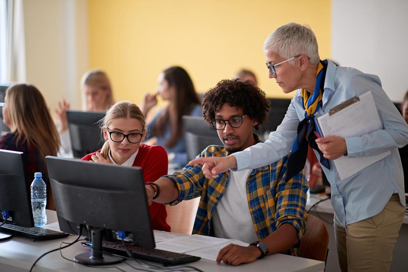 Professor helping a college student in a computer class