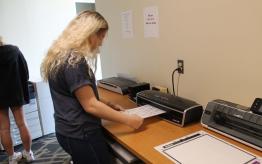 Center for Technology and Online Programs Resource Area with student using the laminator