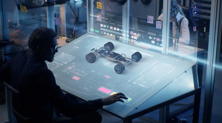 Electrical engineer at workstation with autonomous unmanned vehicle model on screen