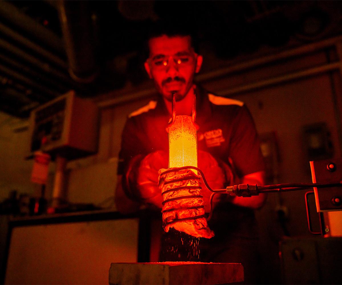 A student carefully removes an item from a fiery furnace.