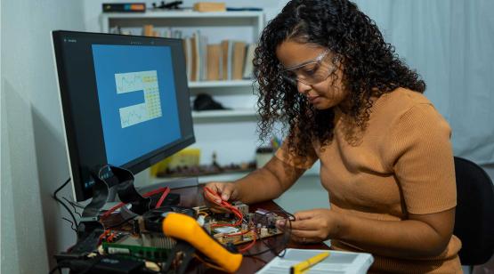 Woman at desk working on the electrical engineering components of a motherboard