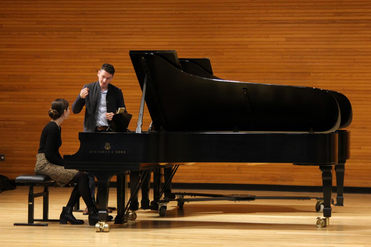 Two people in conversation on a grand piano at Ohio University