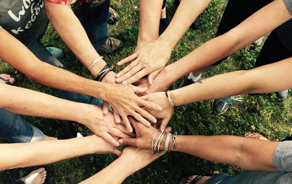 people standing in a circle with hands in the middle