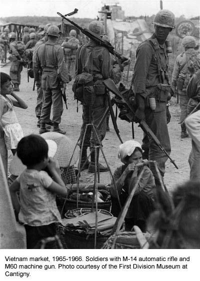 Soldiers with rifles and machine guns in a market in Vietnam, 1965-66