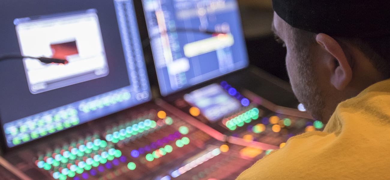 student working at a mixing console in a studio