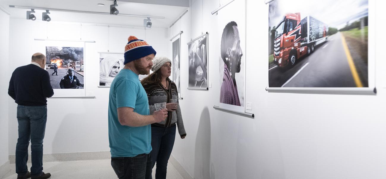 3 people in an art gallery looking at art on the walls 