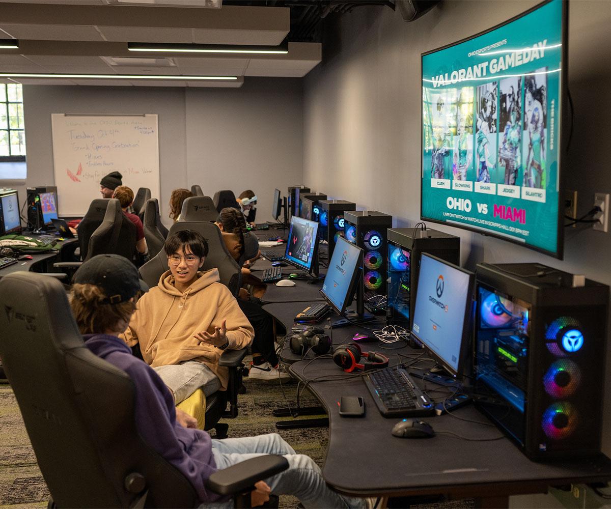 Students talk while sitting at the computers in the Esports gaming room.