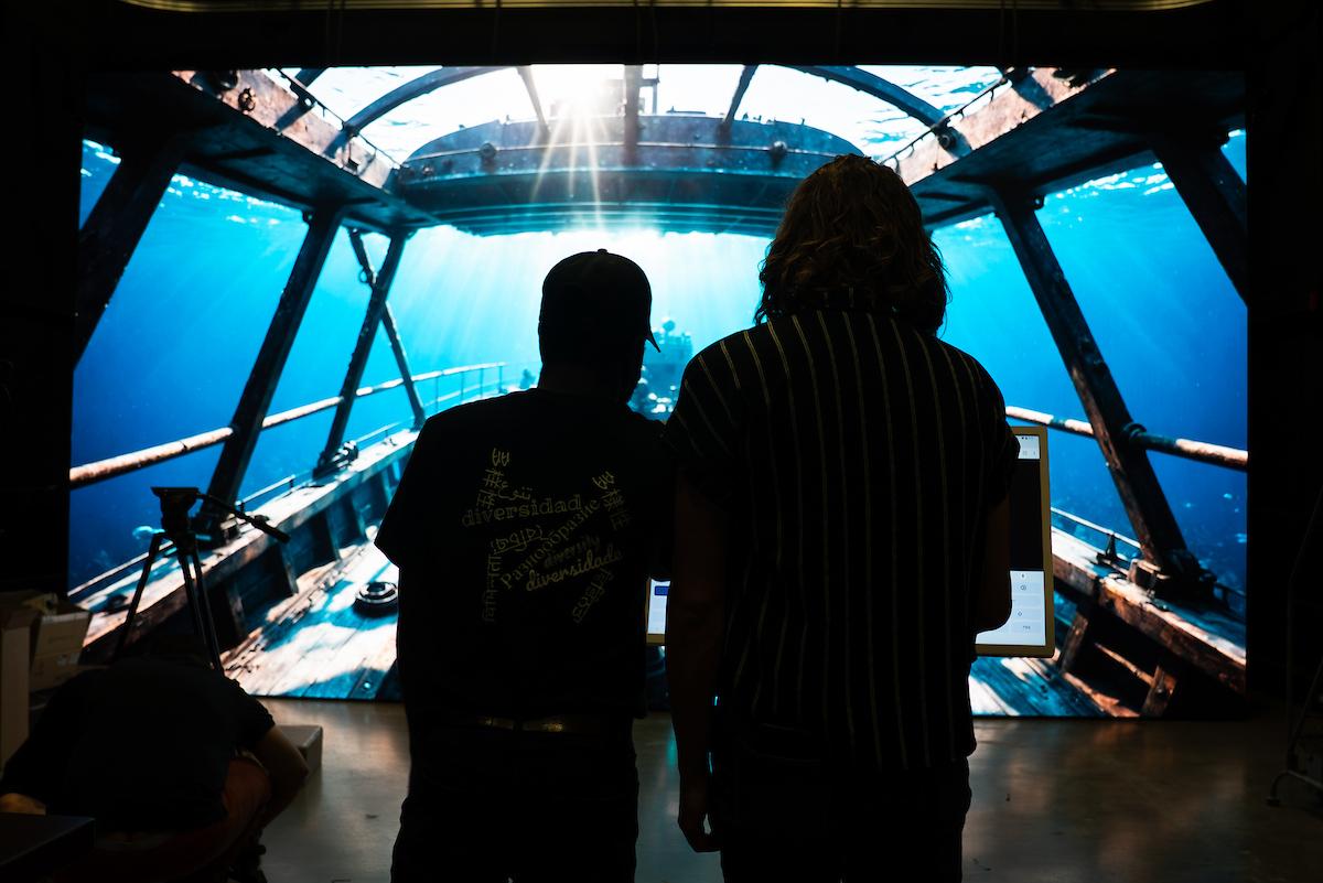 Two students stand in front of an LED wall