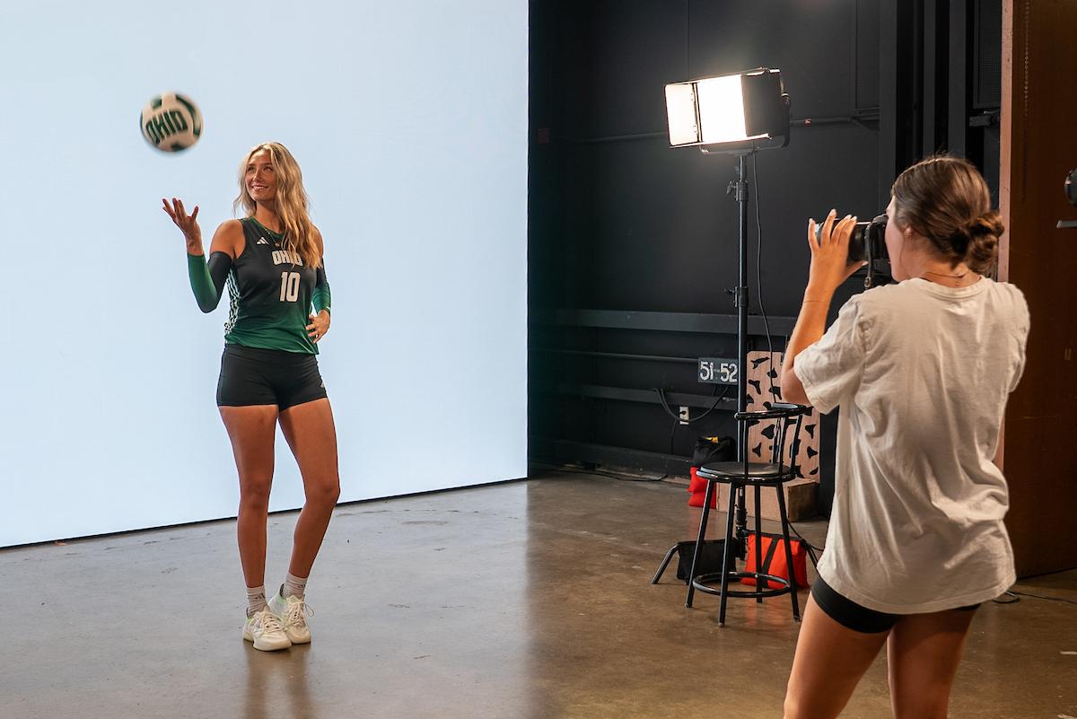 Student photographs a student athlete in front of a high-tech LED wall