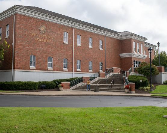 A two story brick building with white trim and a wide stone staircase.