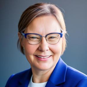 Woman with glasses and blazer smiling in headshot