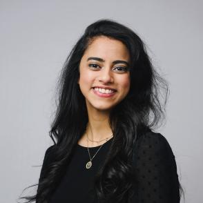 A photo of a smiling woman in front of a gray background