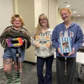 three students showing their art they made at a program