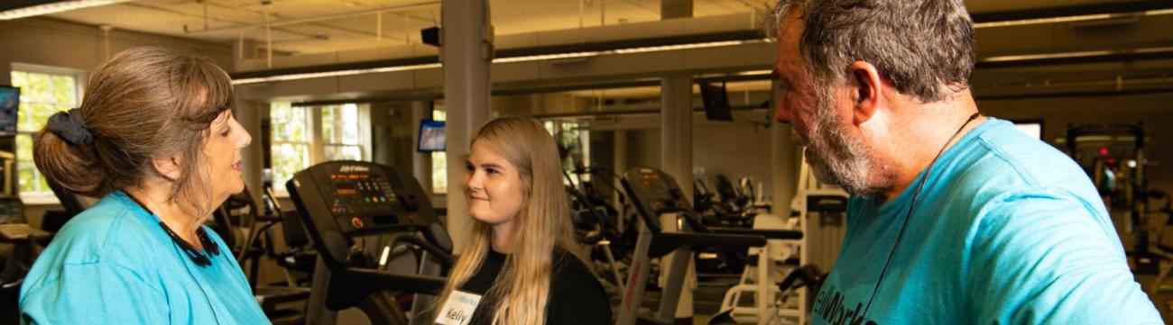 2 Members talking to personal trainer in fitness center