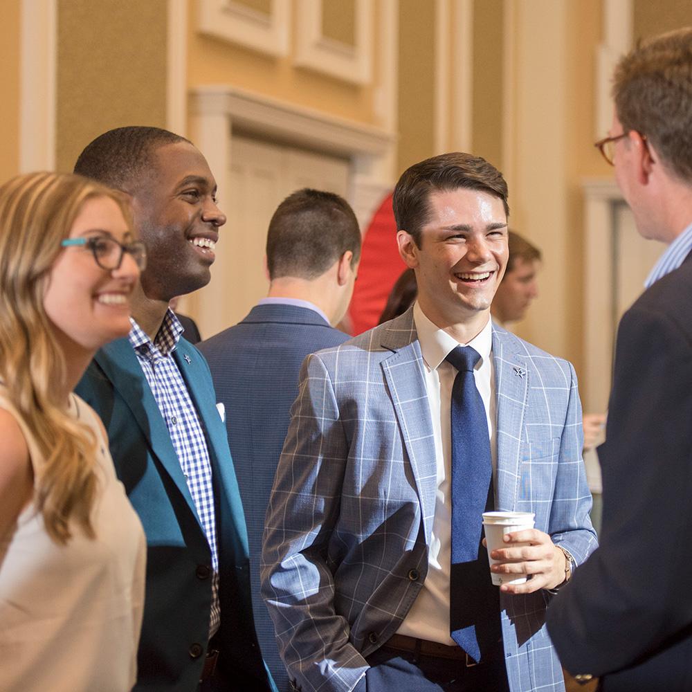 Individuals stand together talking and laughing