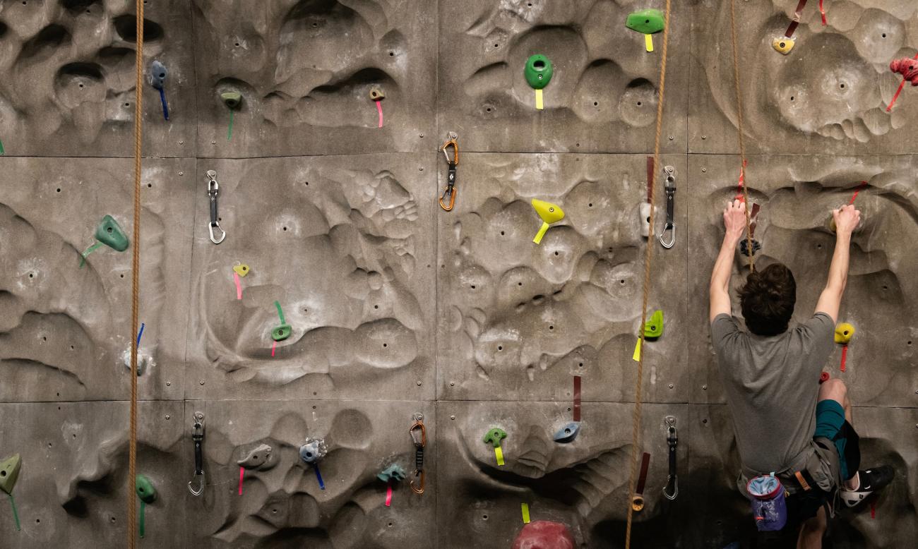 Student climbing a climbing wall. 