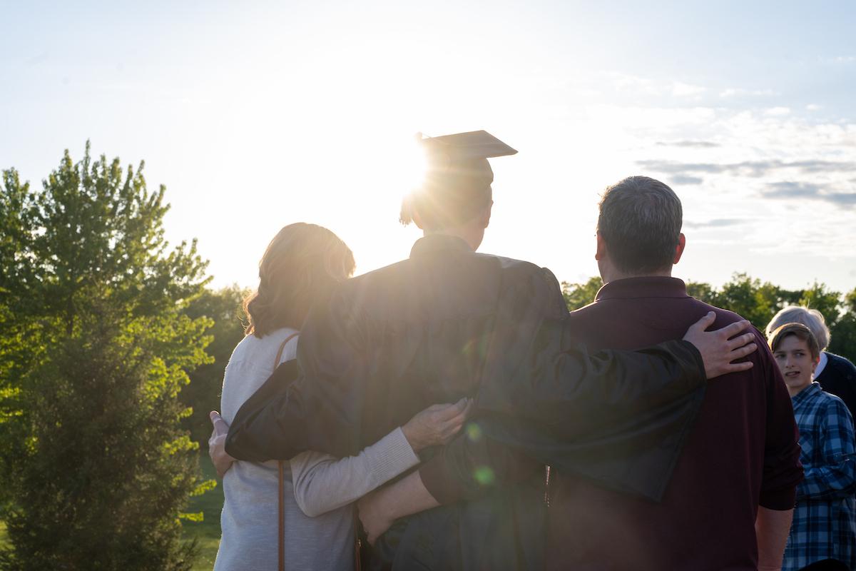 A student embraces family members after commencement.