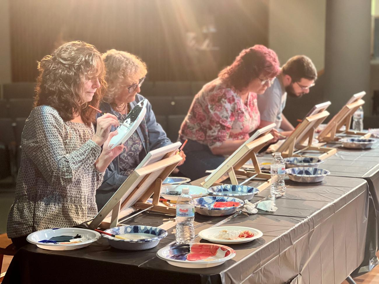 3 woman and 1 male painting in an art class