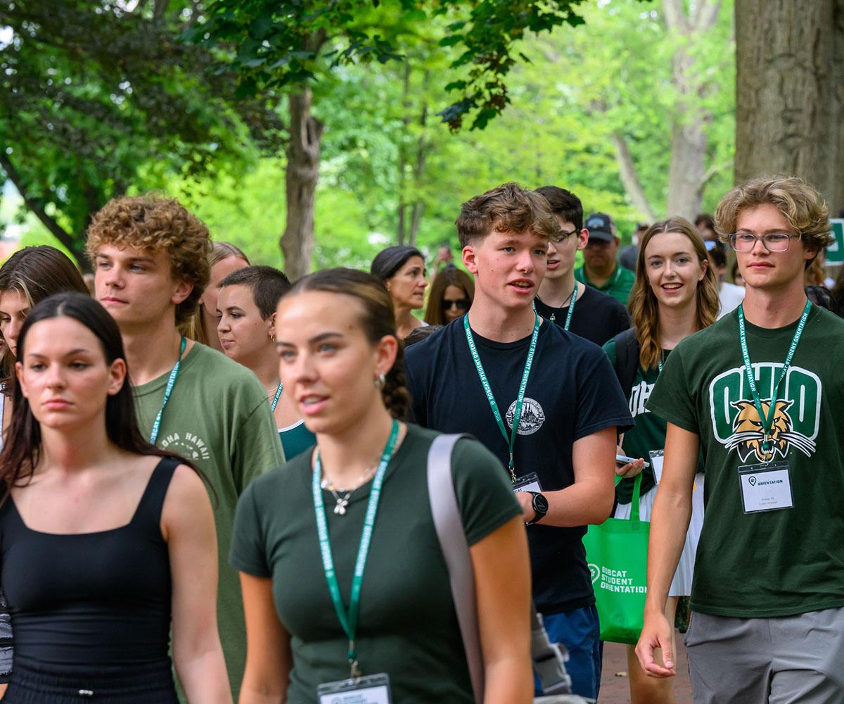 Students walk through campus to an orientation session.