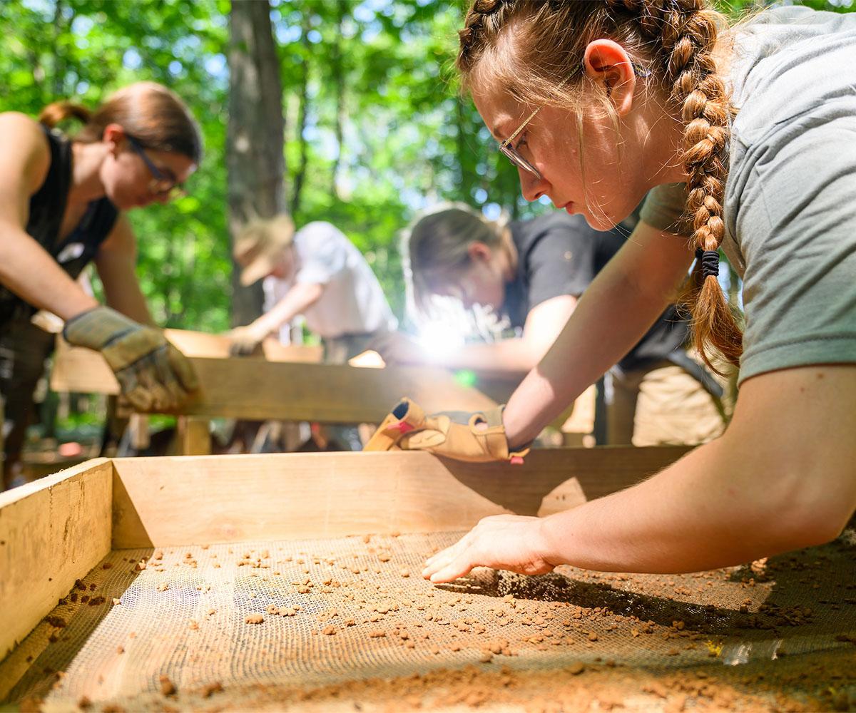 Students inspect the land for artifacts.