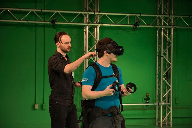 A student helping another student put on virutal reality equipment