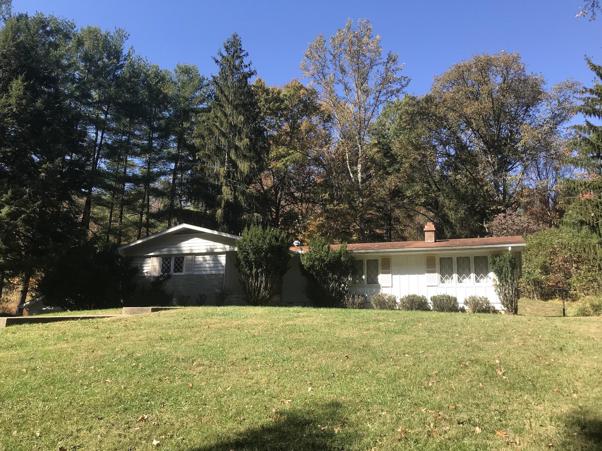 Ranch-style house with lawn in front and trees in back