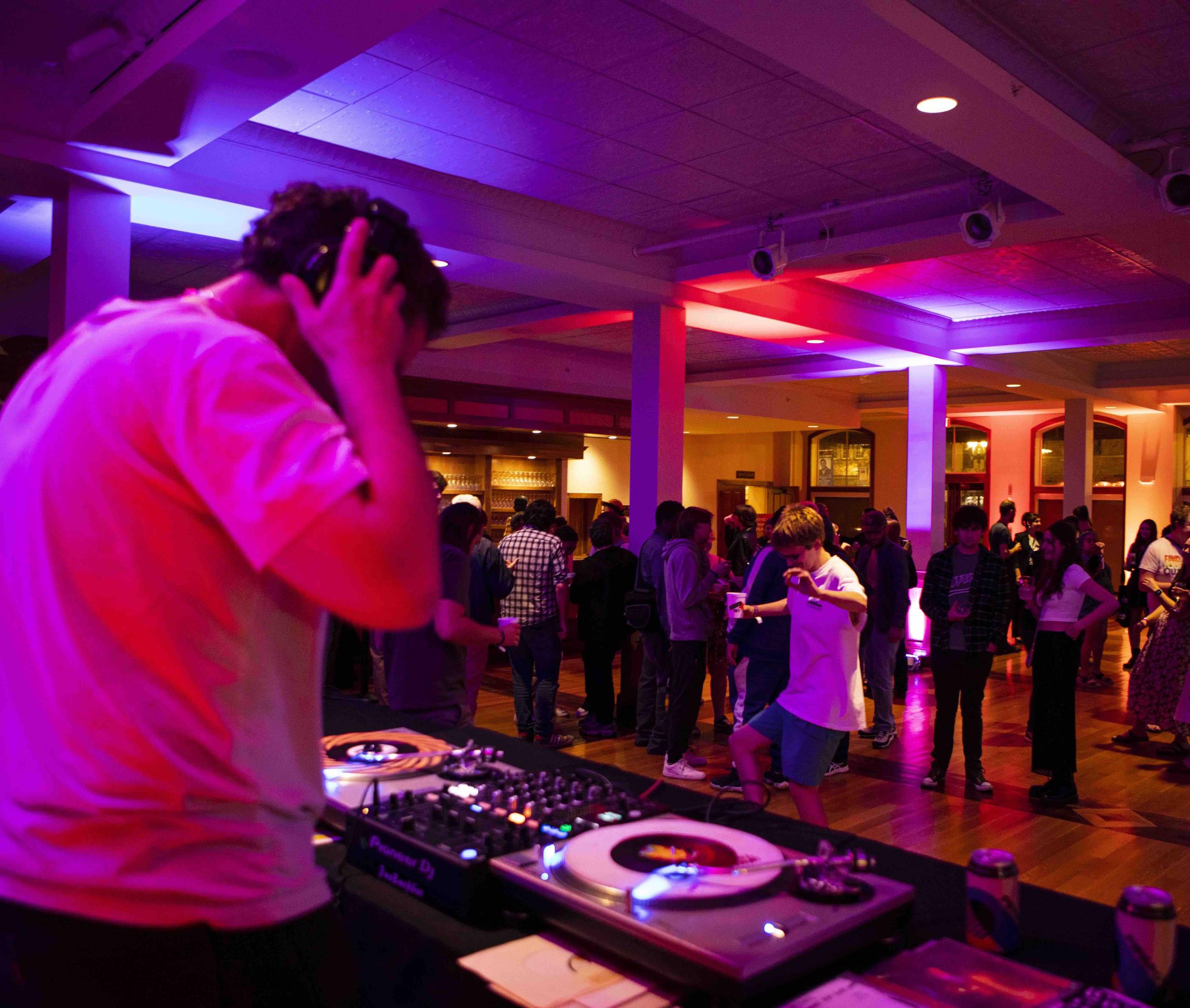 A. Savage listening to headphones while DJing and people talking and dancing in front