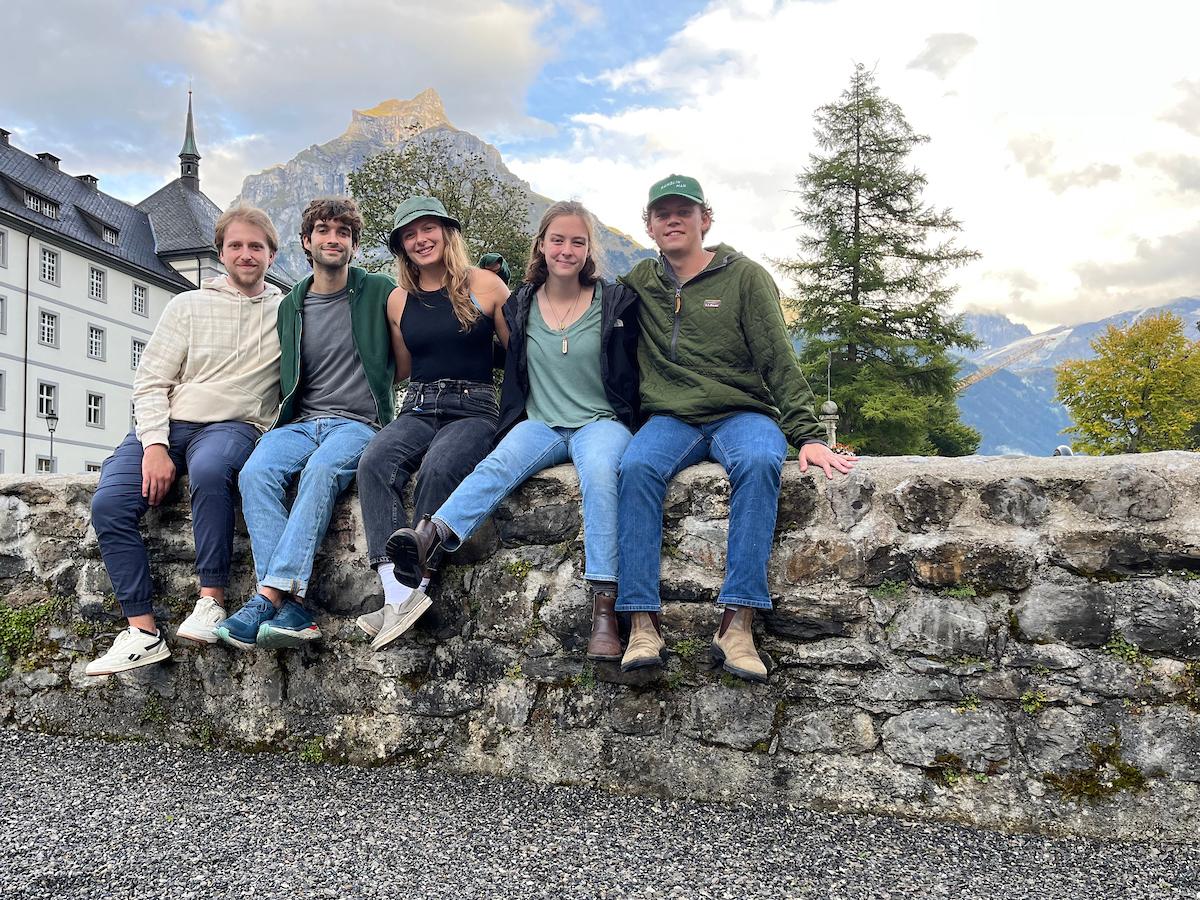 Five students sitting on wall in Switzerland.