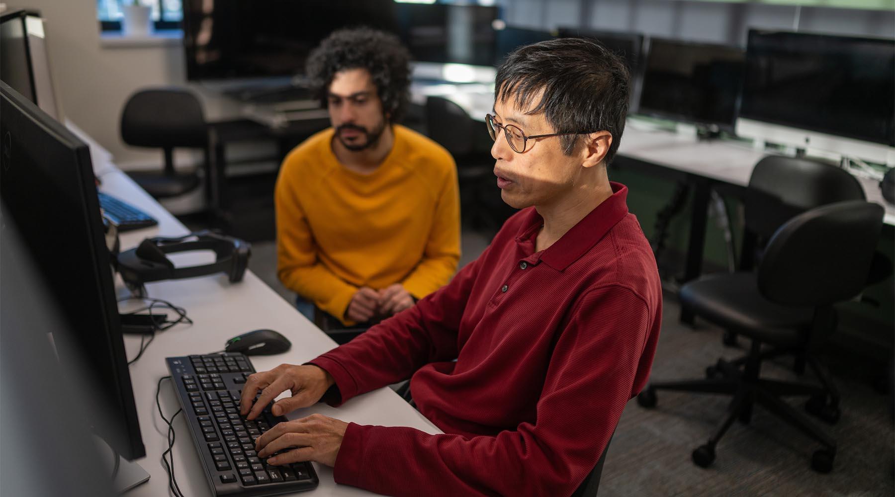 Two people working on a computer together.