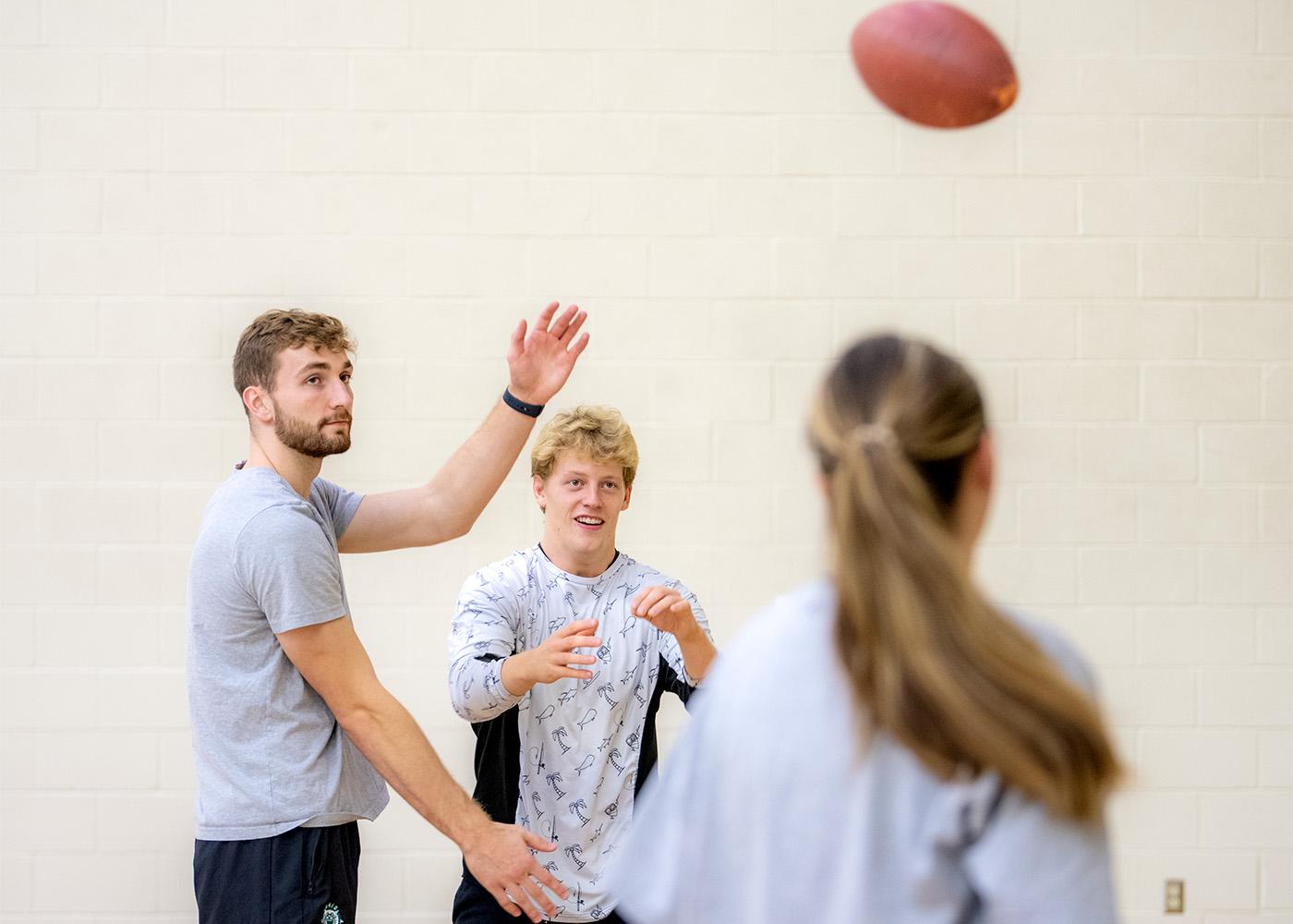 Students play football in the gymnasium.