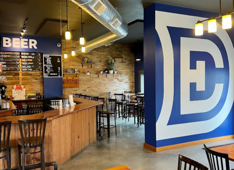 Inside of the Double Edge Brewing Taproom showing bar area and DE logo on interior wall.
