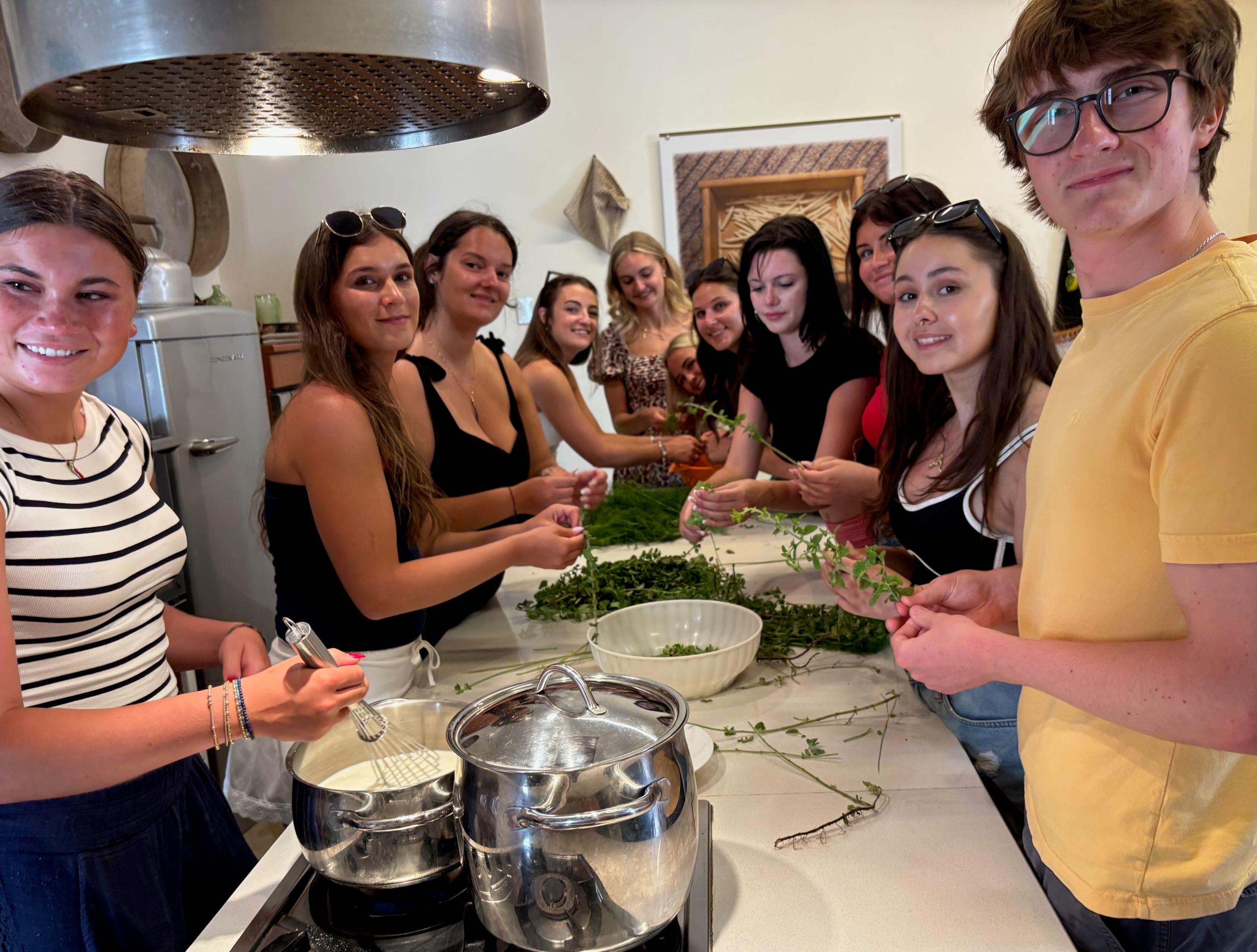 A group of students suround a table where they preparing greens for cooking