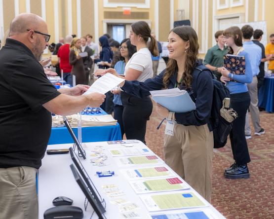 young woman talking to a man at a booth at a career fair